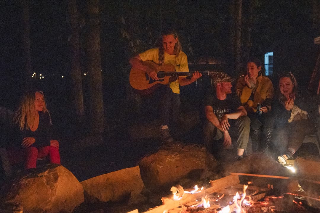 Person playing guitar at a campfire with friends