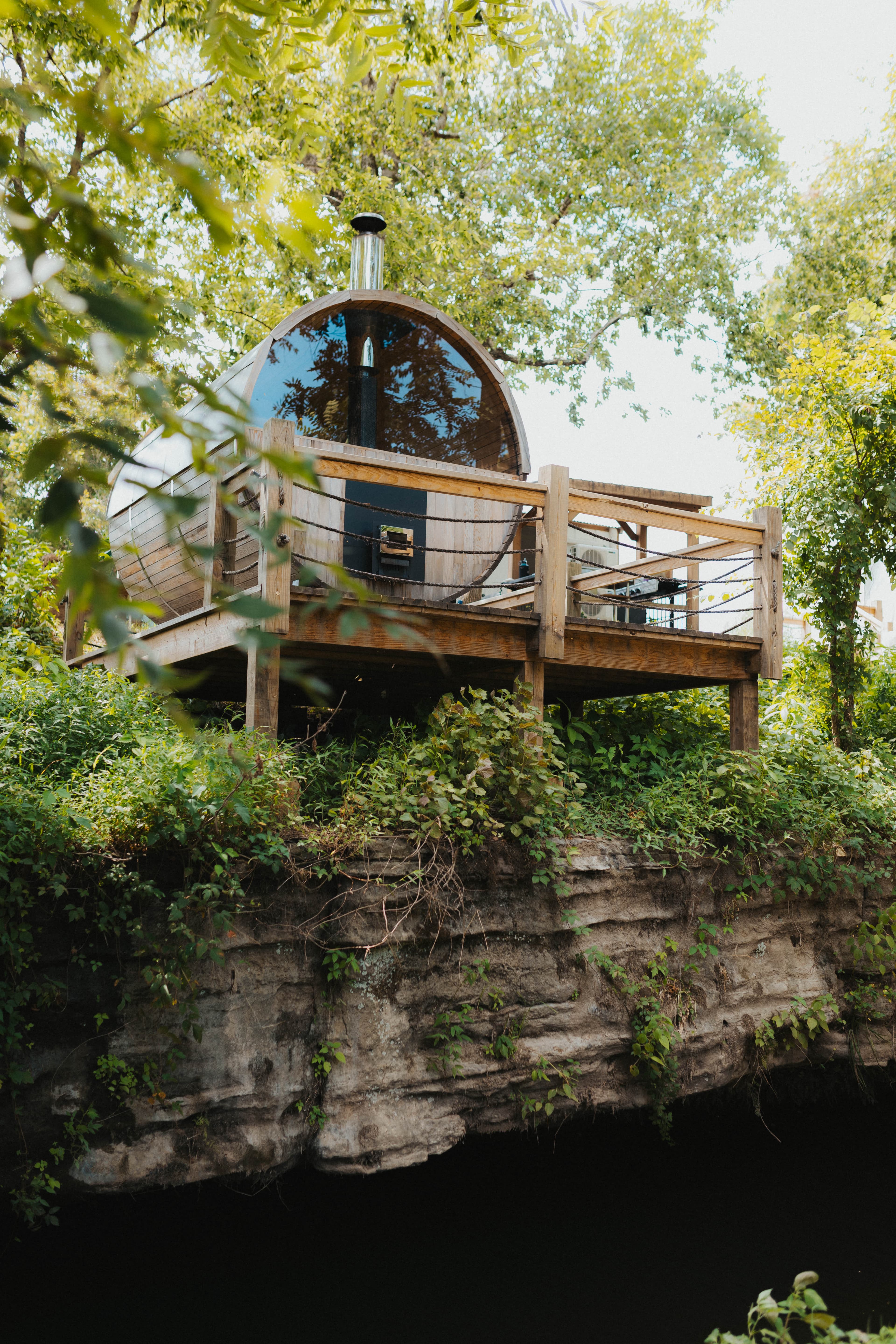 Wood barrel sauna perched on a wooded hillside