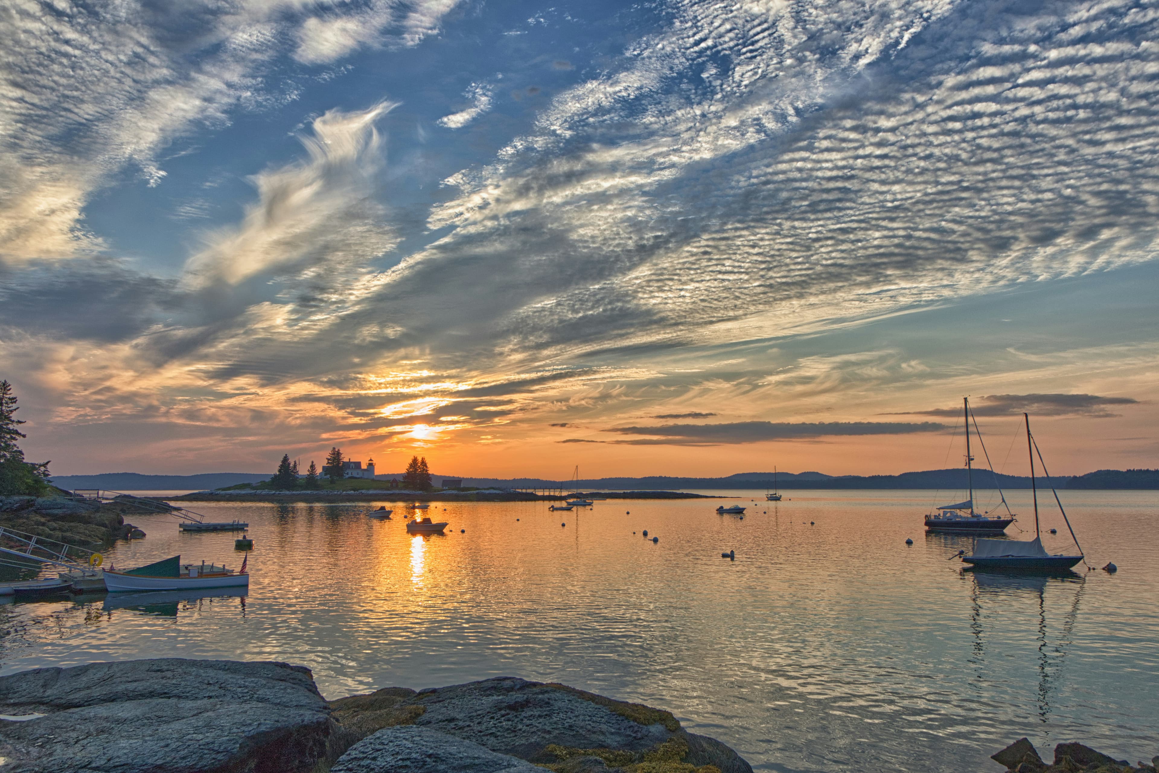 Sailboats moored in a quiet harbor at sunset