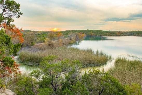 Sunset over the lake at Cleburne State Park with fall color along the shore