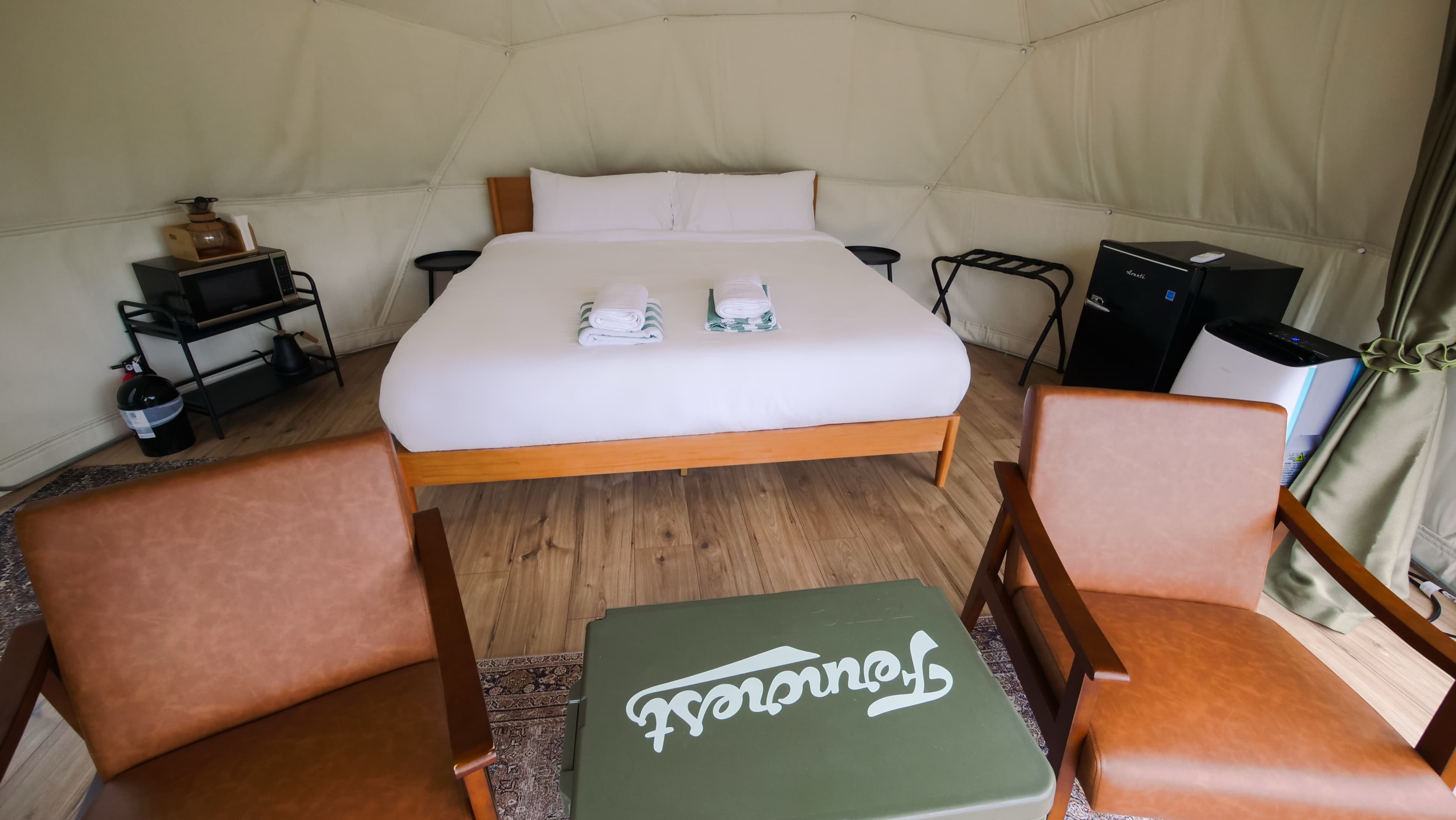 The king bed, leather chairs and Ferncrest cooler inside a Classic Dome