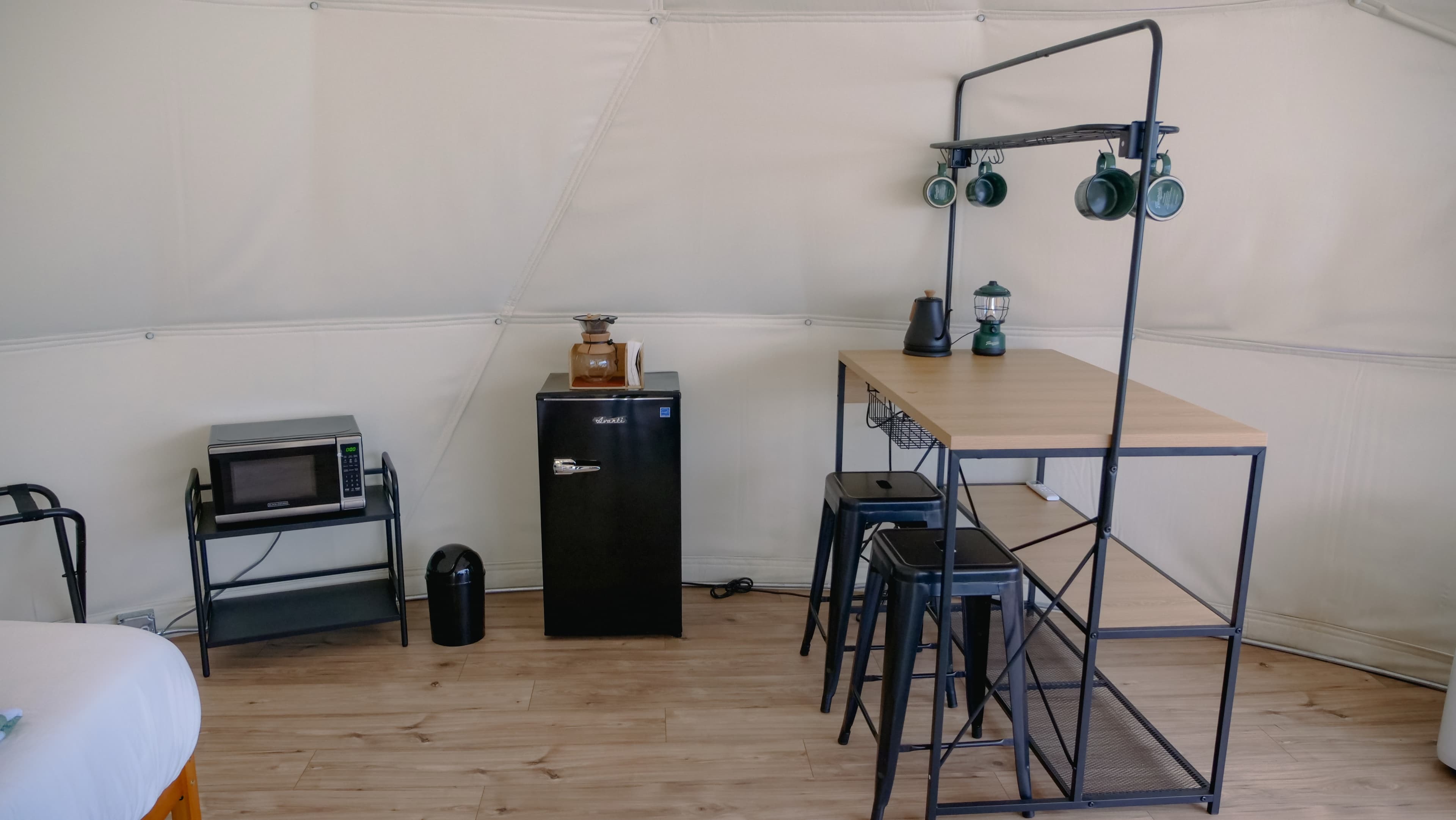The kitchenette corner of a Family Dome, with mini fridge and stools