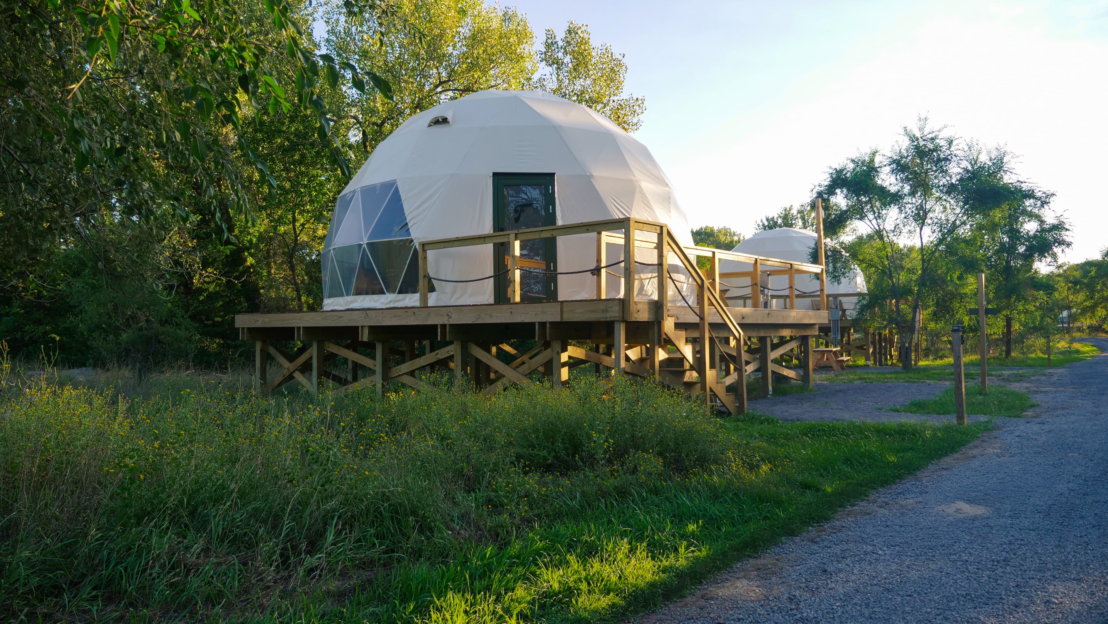 A dome on its raised deck beside the gravel path, with a second dome behind