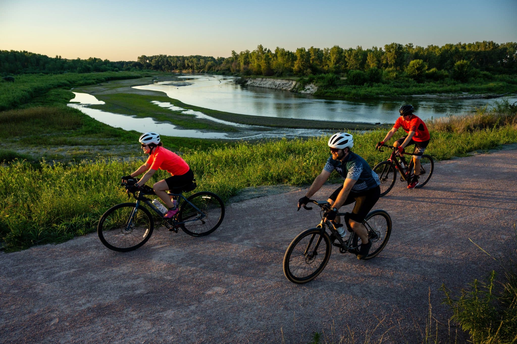 Cyclists riding the Cowboy Trail beside the river at golden hour